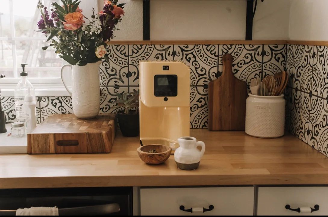 A cream LĒVO II+ infusion machine on a butcher block kitchen counter